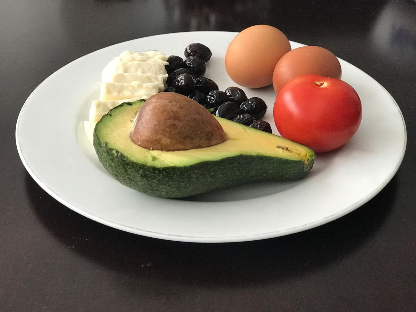 healthy keto diet plate with avocado eggs cheese and fresh vegetables